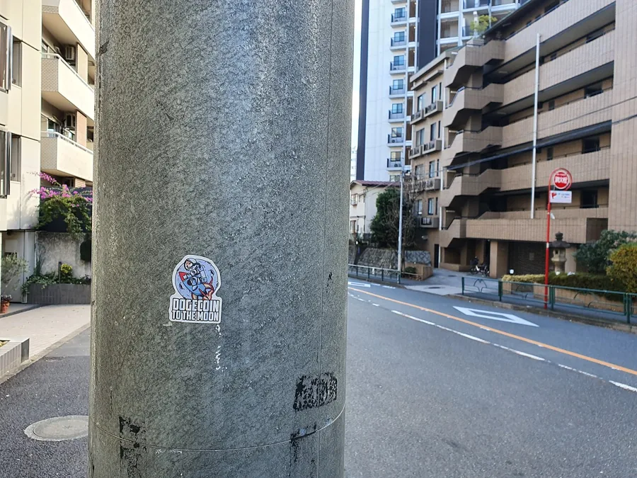 A dogecoin sticker on a pole in Tokyo: wen moon, in the physical world.